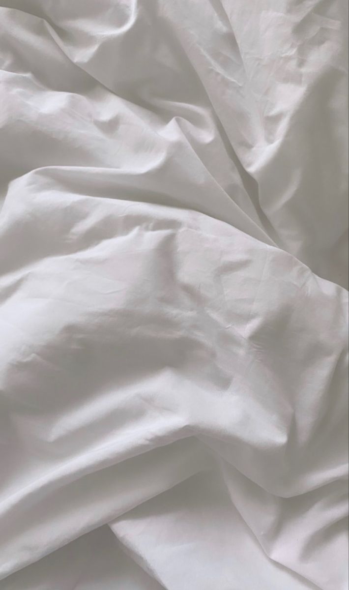 an unmade bed with white sheets and pillows