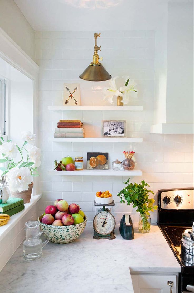 a kitchen with white walls and shelves filled with fruit on the counter, along with an oven