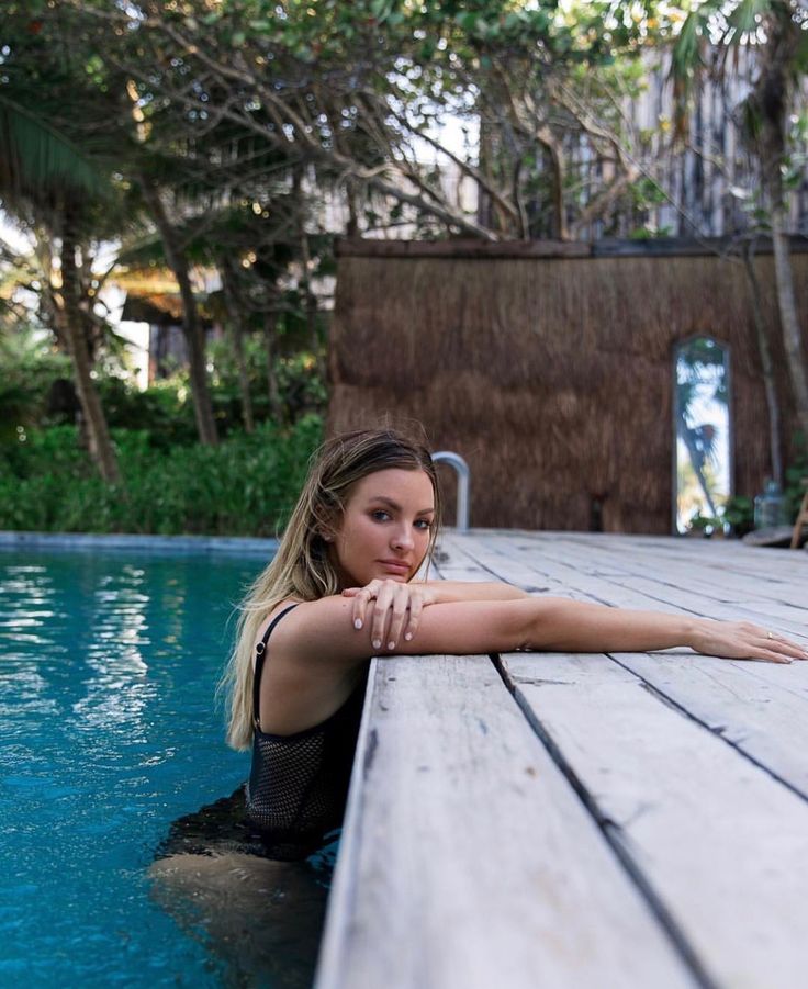 a woman leaning on the edge of a pool