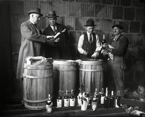 three men are standing around some barrels with bottles