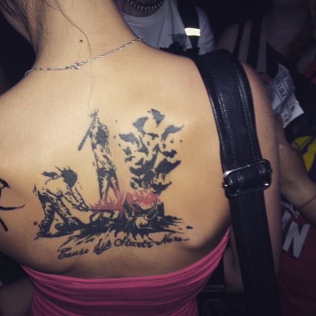 the back of a woman's shoulder with an inked sailboat on it