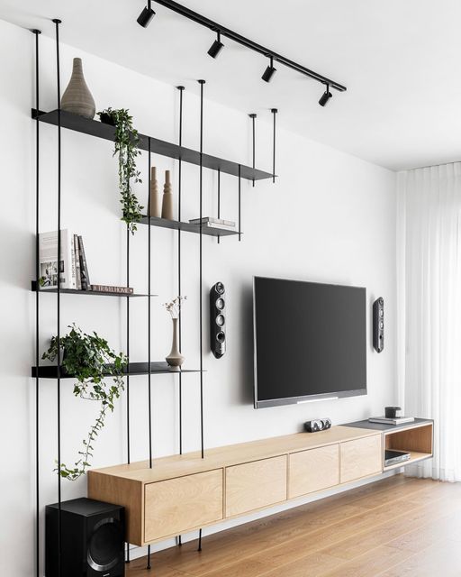 a flat screen tv sitting on top of a wooden shelf next to a wall mounted speaker