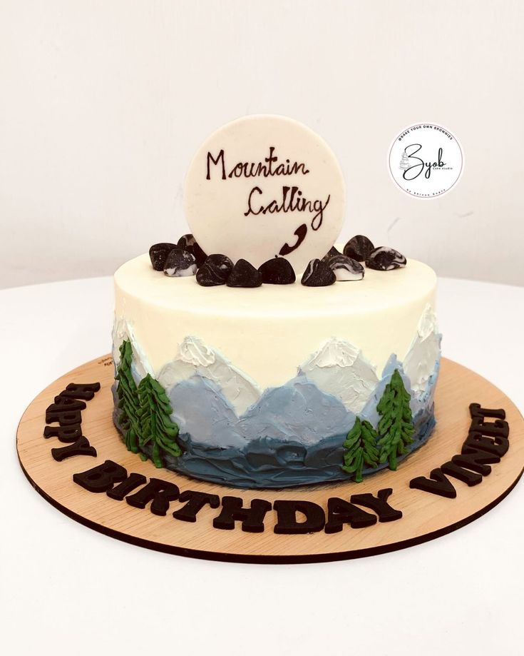 a birthday cake is decorated with mountains and trees on the top, which reads mountain crafty