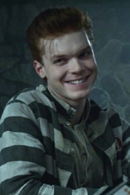 a young man smiling and holding a knife in his hand while wearing a striped shirt