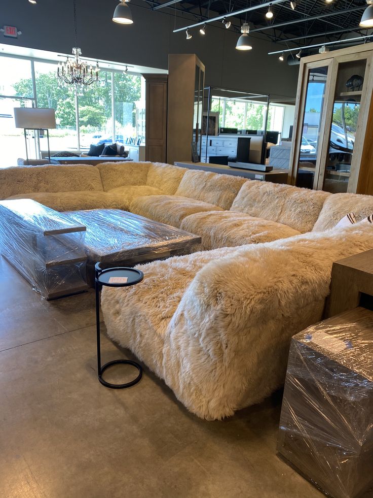 a large sectional couch in a showroom with boxes on the floor and other furniture