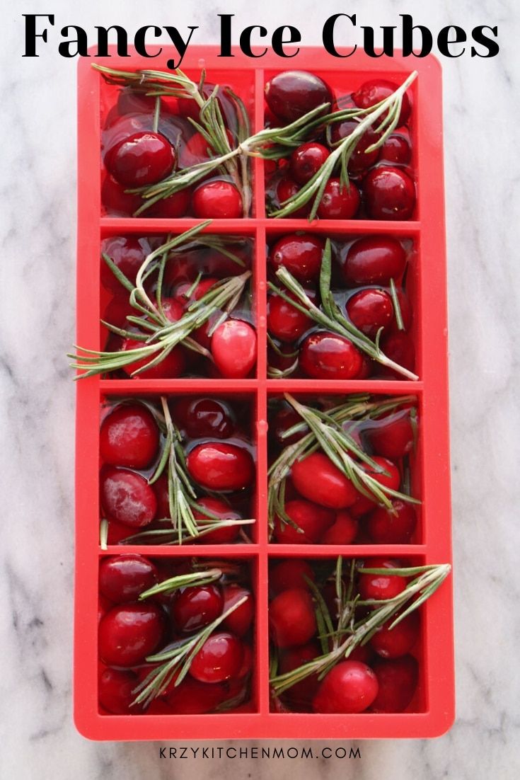 an ice cube filled with cherries on top of a marble counter next to text overlay that reads fancy ice cubes