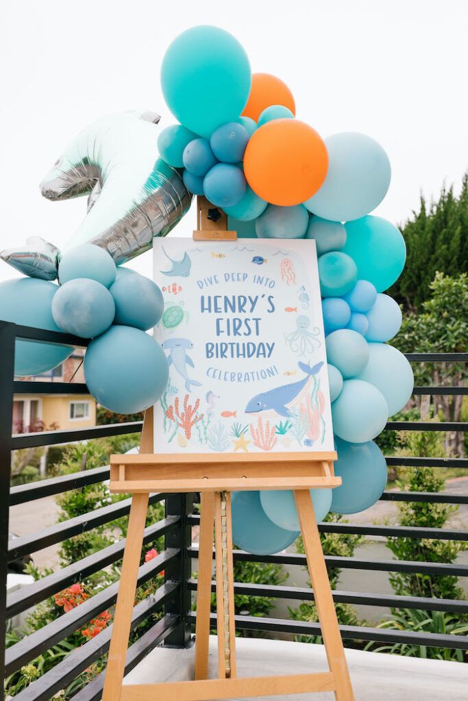 a sign with balloons attached to it that says henry's first birthday