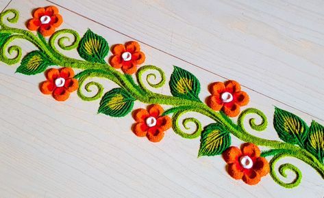 an embroidered design with orange flowers and green leaves on white wooden background, closeup