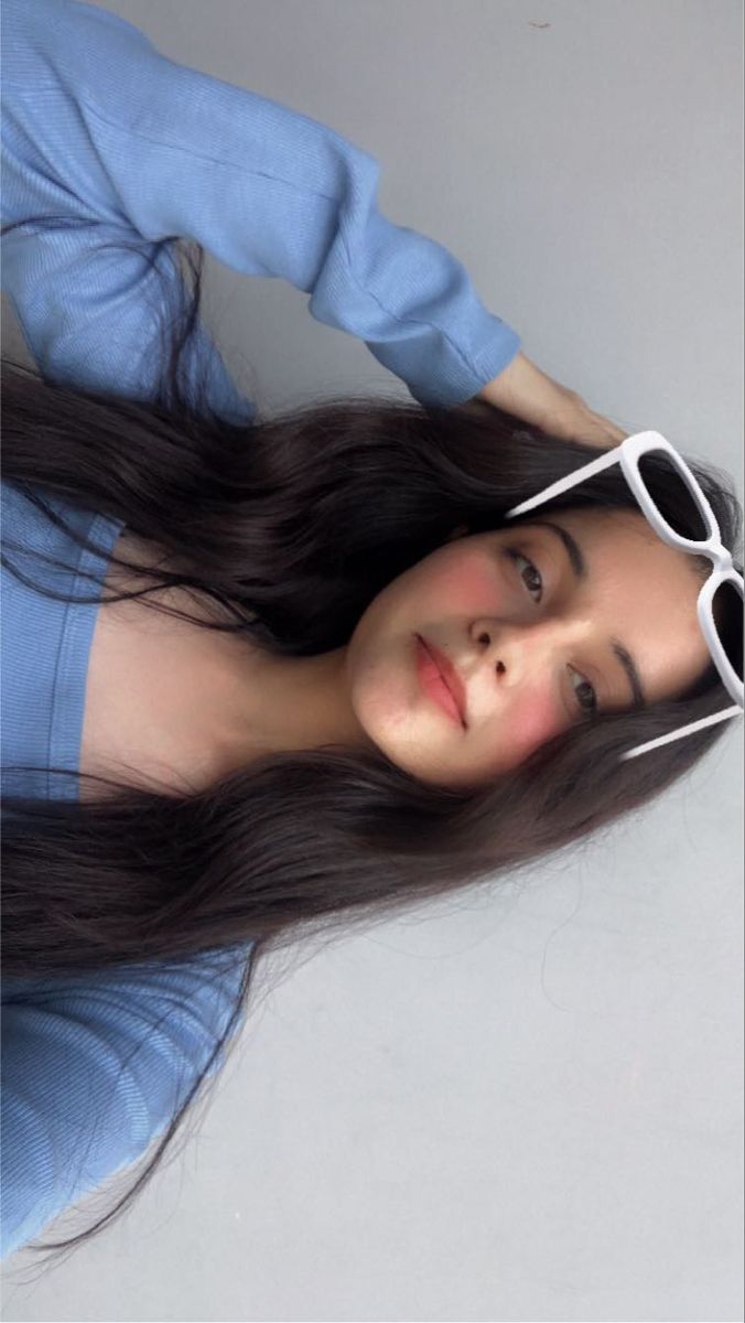 a woman with long hair and sunglasses on her head is posing for the camera while wearing a blue shirt