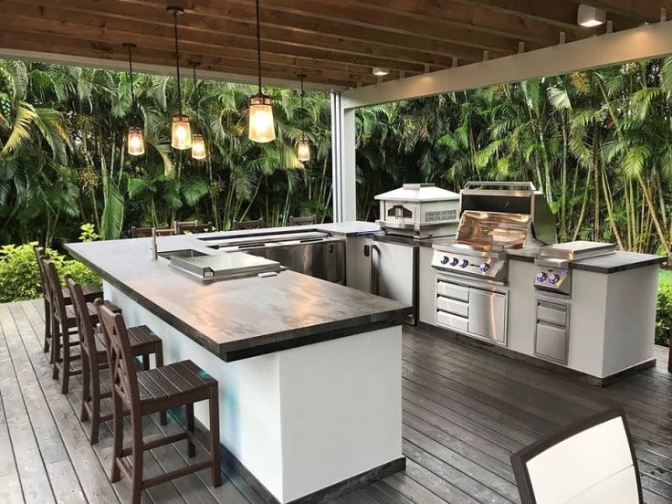 an outdoor kitchen with lots of counter space and lights hanging from the ceiling above it