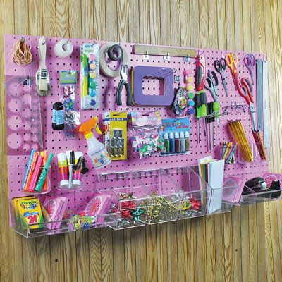 a pink pegboard with lots of crafting supplies on it hanging from the wall