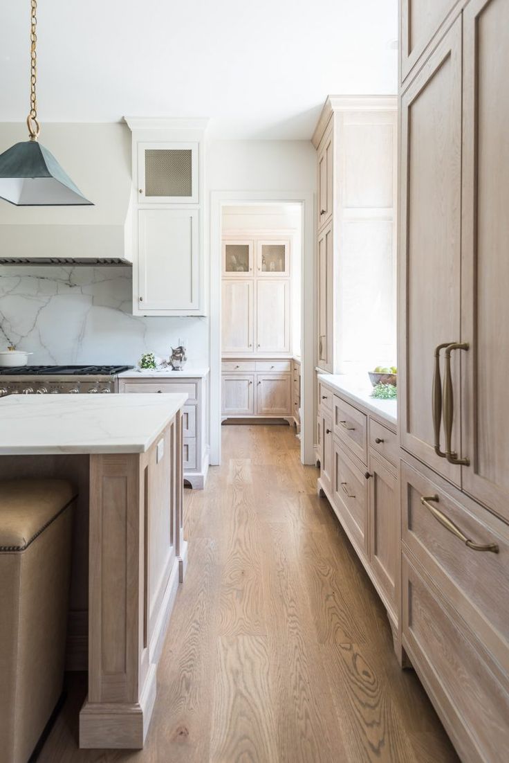 a kitchen with white cabinets and wood floors, along with an island in the middle