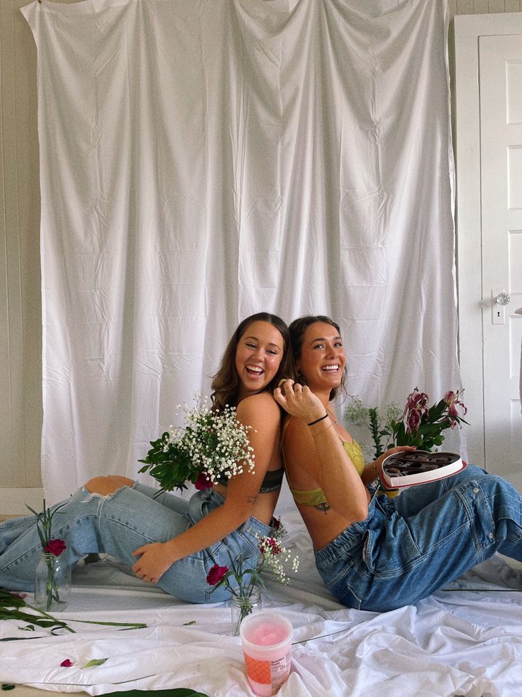 two women sitting on the bed with flowers