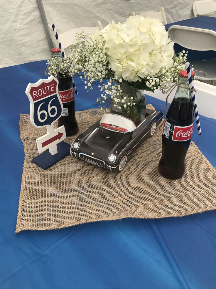 a table topped with vases filled with white flowers and two old fashioned route 66 signs