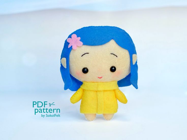 a small stuffed doll with blue hair wearing a yellow dress and flower in her hair