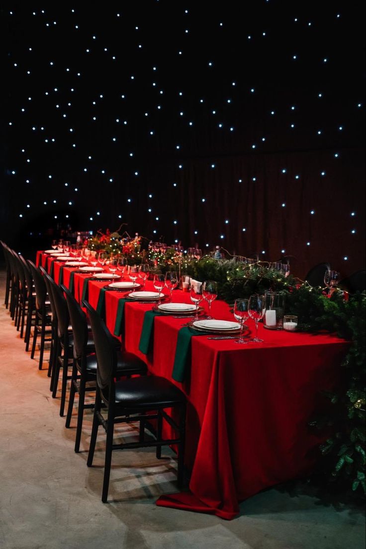 a long table is set up with red cloths and place settings for an event