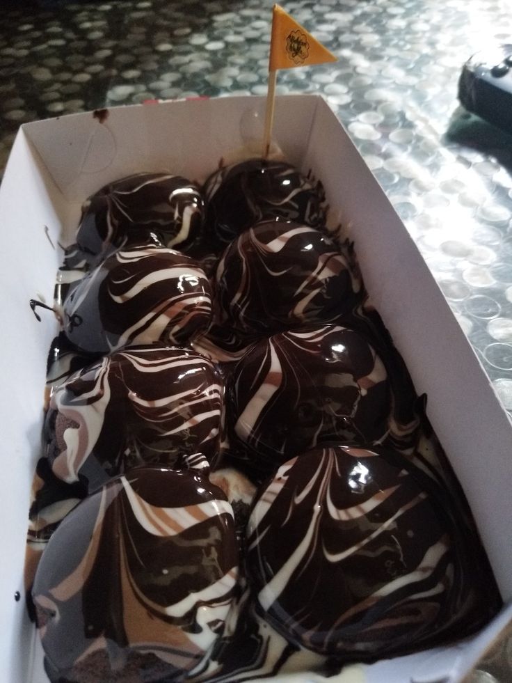 a box filled with chocolate covered donuts on top of a table