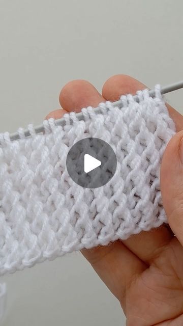 a person holding a knitted object with a needle in it's palm and thumbnail