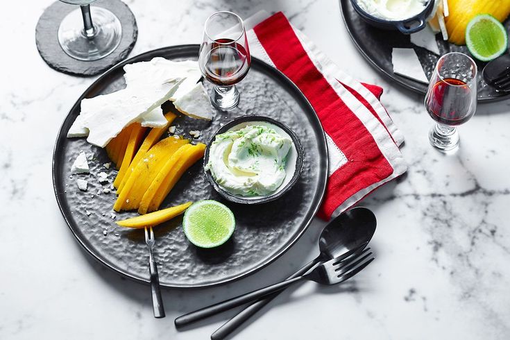 two plates filled with food and drinks on top of a white tablecloth next to silver utensils