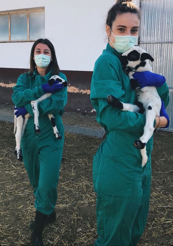 two women in green jumpsuits holding goats