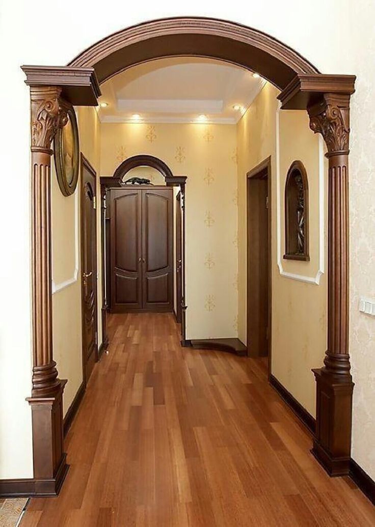 an empty hallway with wooden floors and arched doorways