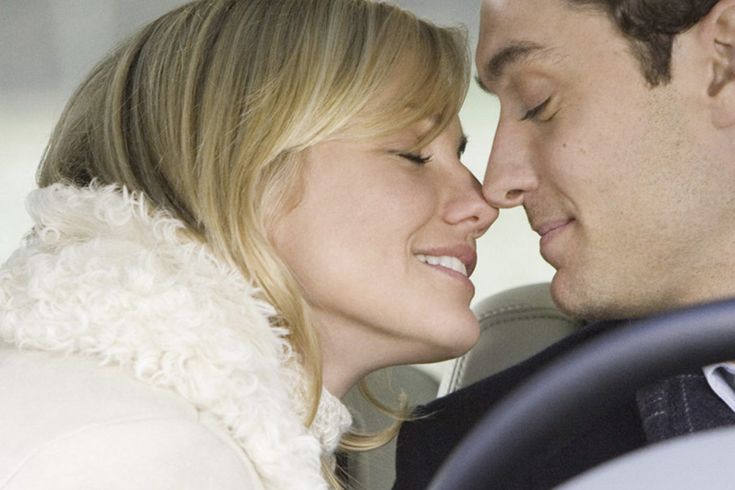 a man and woman are kissing in the back seat of a car while they look into each other's eyes