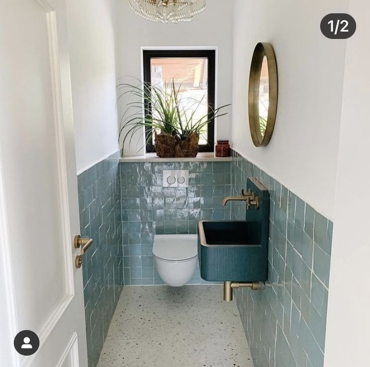 a bathroom with blue tiles and a white toilet in the corner next to a window