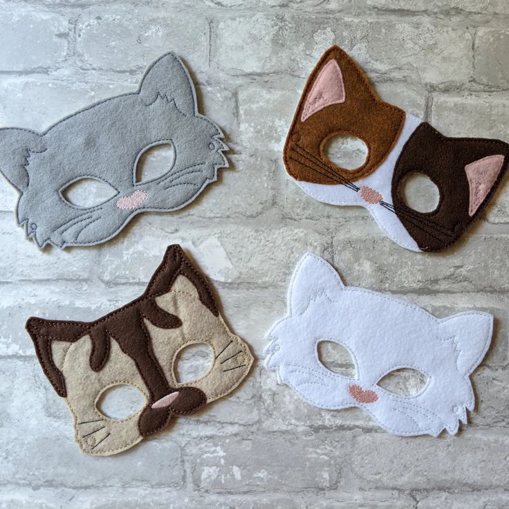 four different masks on a brick wall with one wearing a cat mask and the other wearing a fox mask