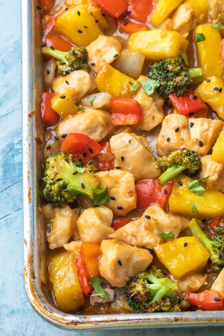 chicken, broccoli and peppers in a casserole dish on a blue surface