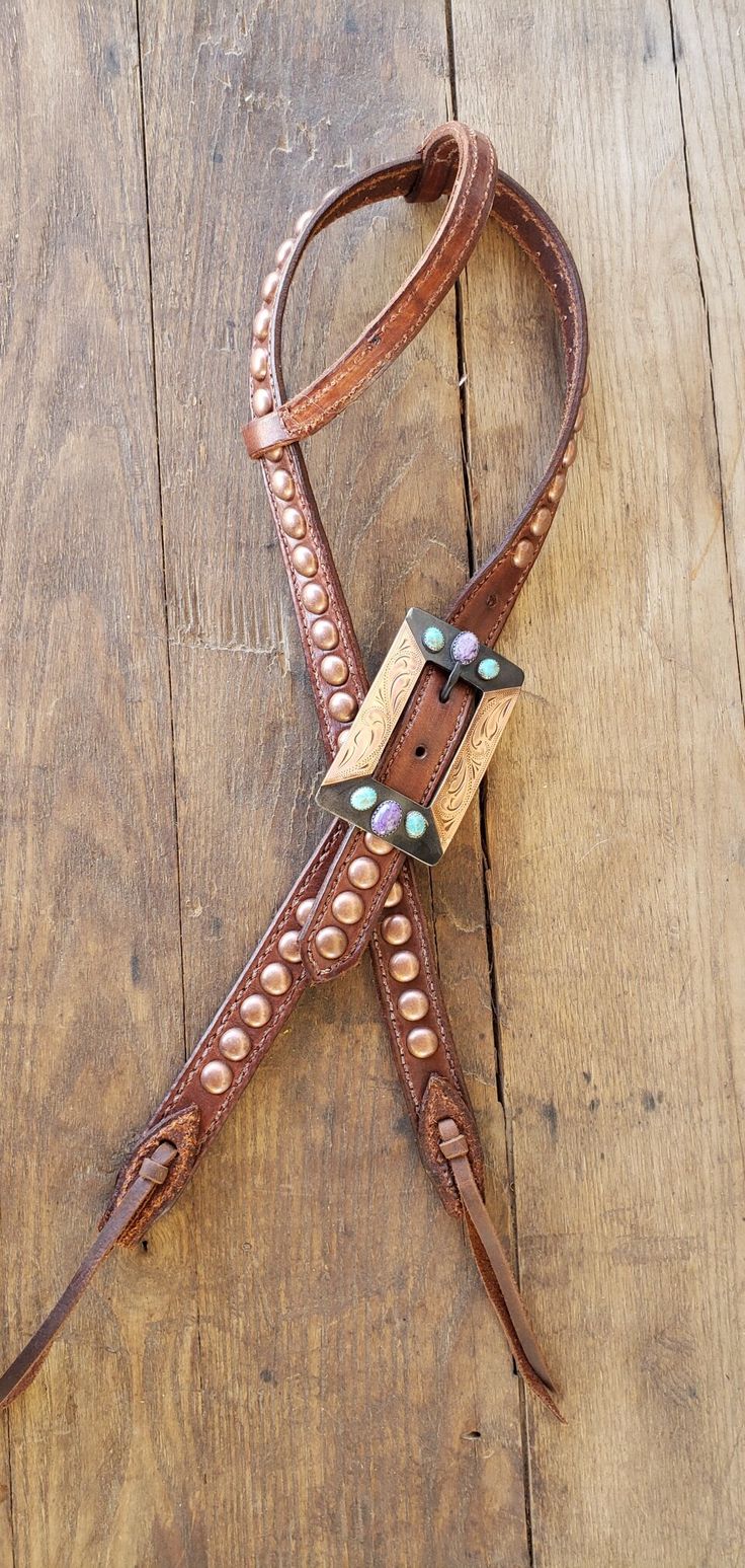 a horse bridle on a wooden floor with beads and leather cord attached to it