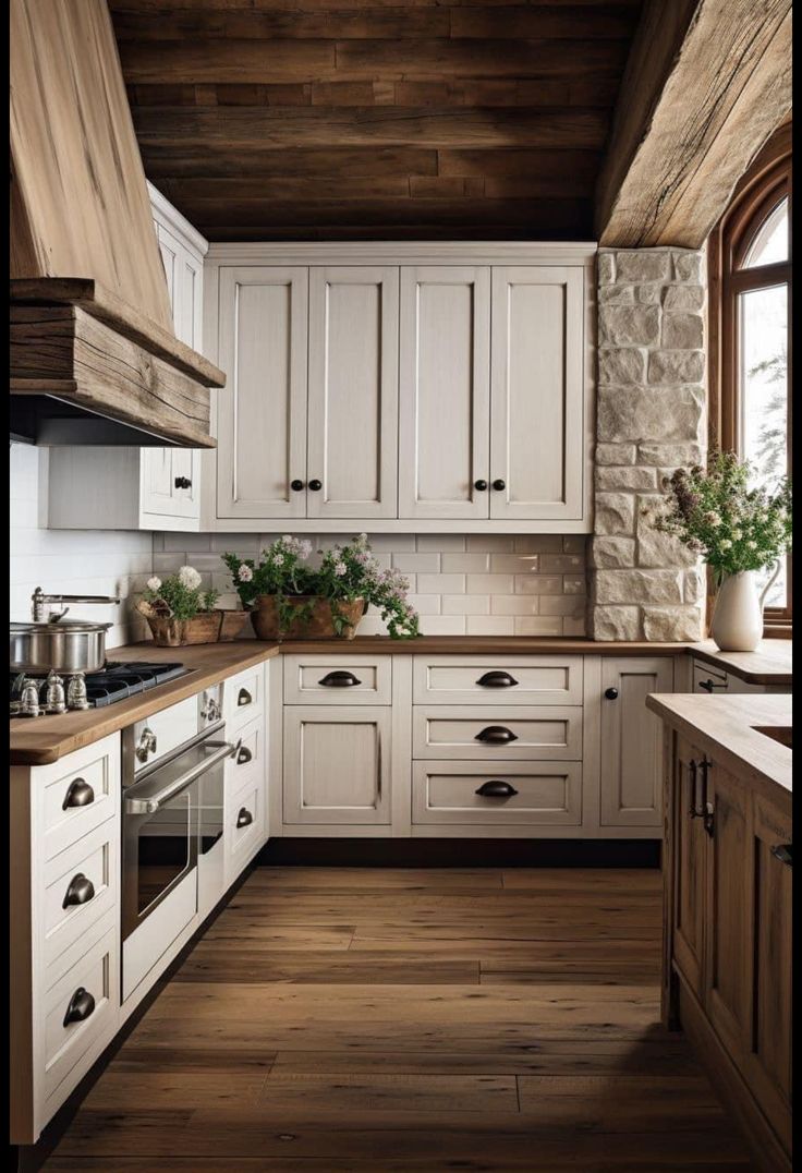 a kitchen with white cabinets and wood floors is pictured in this image, there are potted plants on the counter