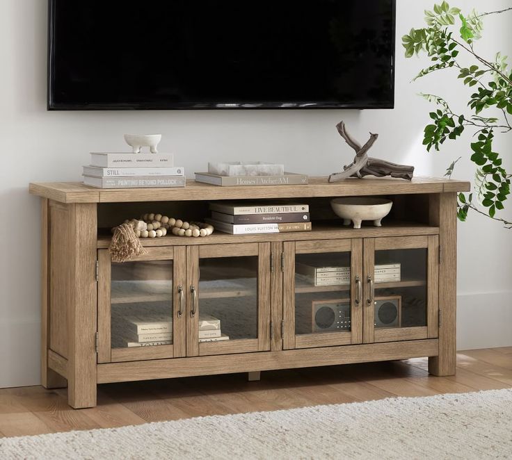 a television is mounted on the wall above a wooden entertainment center with glass doors and shelves