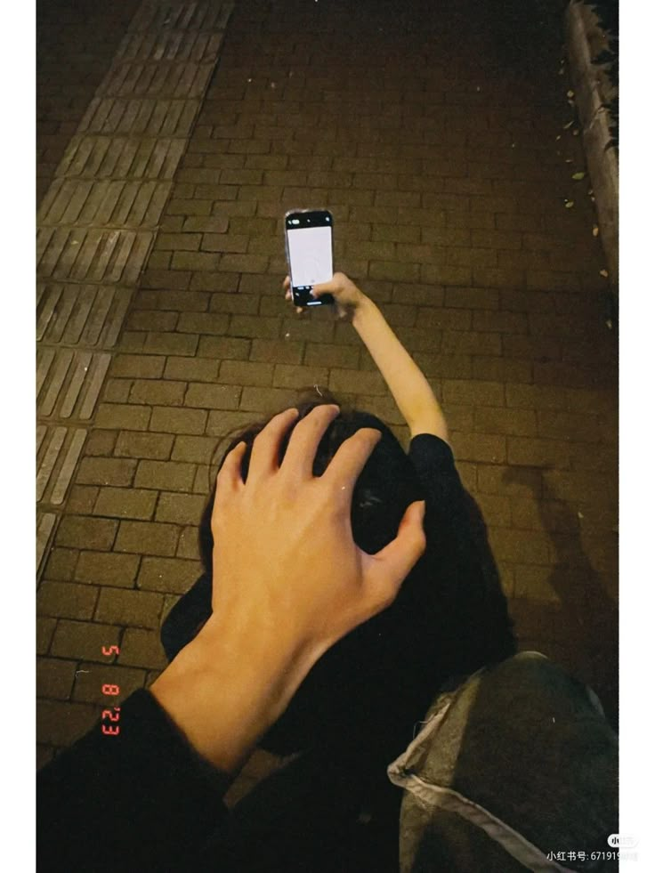 someone is holding up their cell phone to take a photo on the street at night