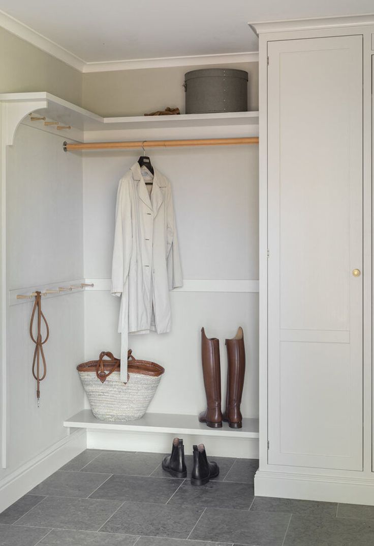 a white closet with shoes and boots on the floor next to a coat hanger