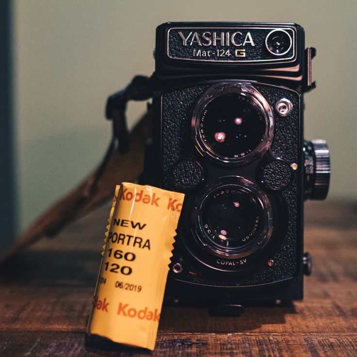 an old camera sitting on top of a wooden table next to a yellow sticker