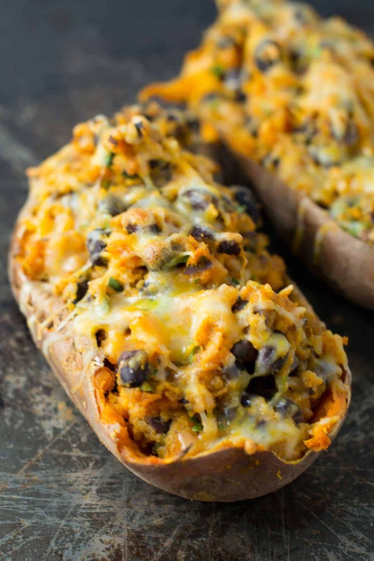 a baked potato with cheese and black olives on it, sitting on a table