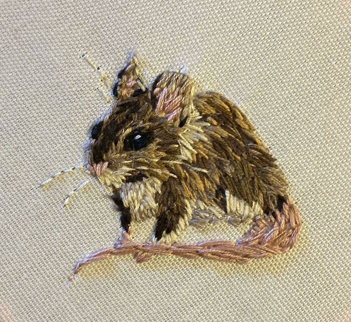 an embroidered mouse sitting on top of a piece of cloth