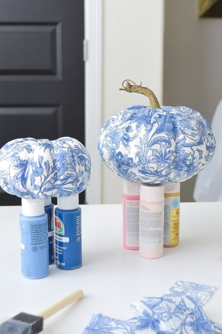 two blue and white pumpkins sitting on top of a table next to some paint