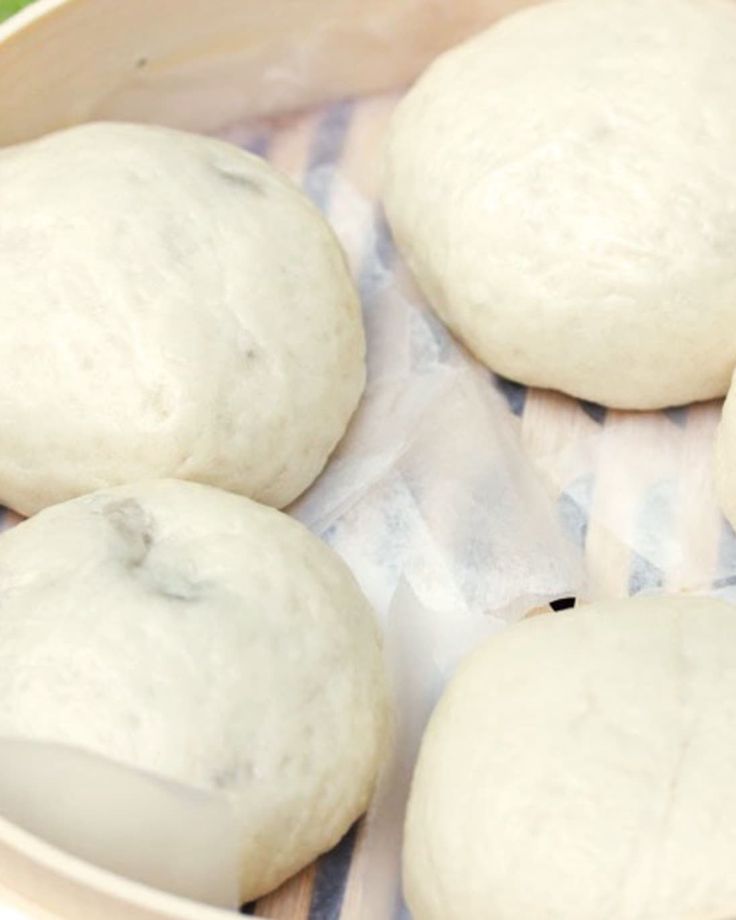 four uncooked doughnuts in a wooden bowl on a tablecloth covered surface