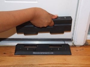 a hand is holding onto the door handle on a black device that has been placed in front of a white door