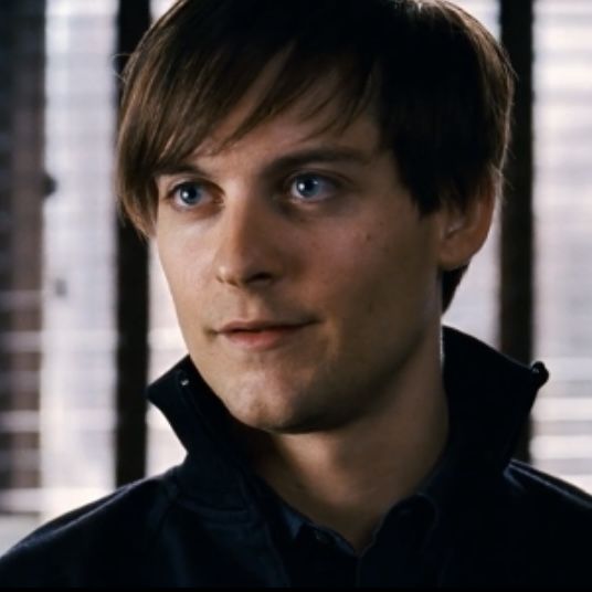 a close up of a person wearing a black shirt and looking at the camera with blue eyes