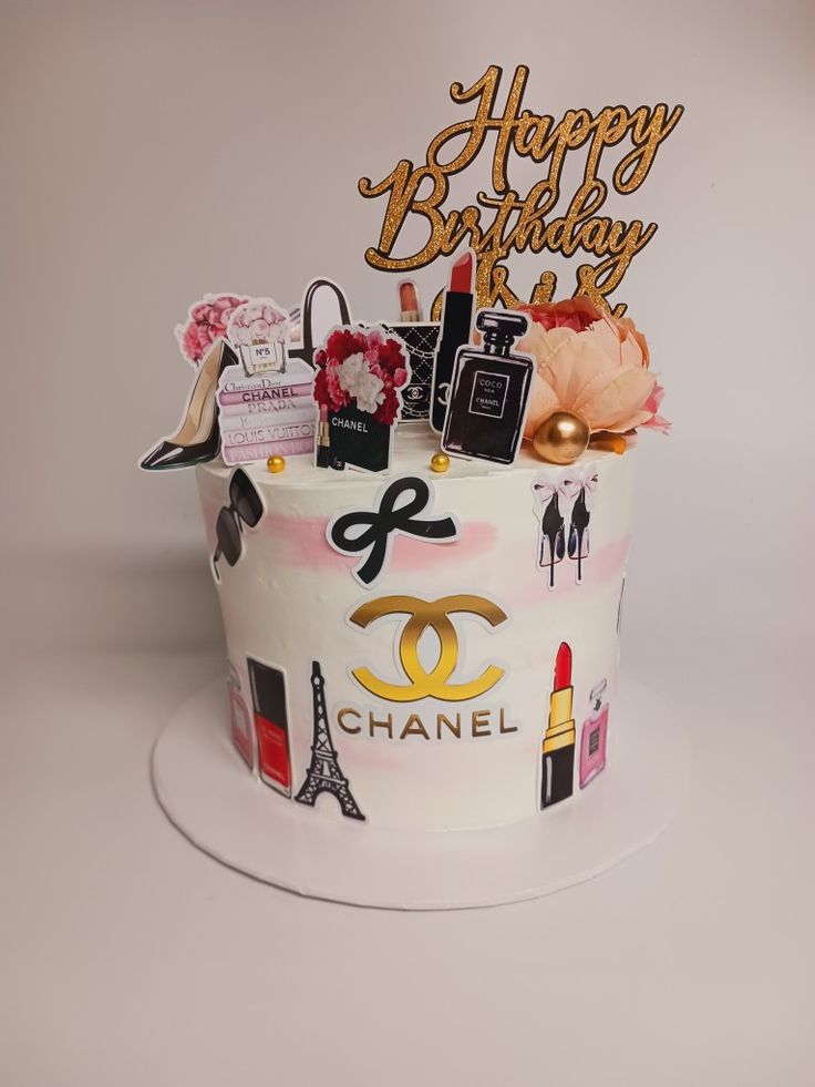 a birthday cake with chanel decorations on it's top and the words happy birthday written in gold