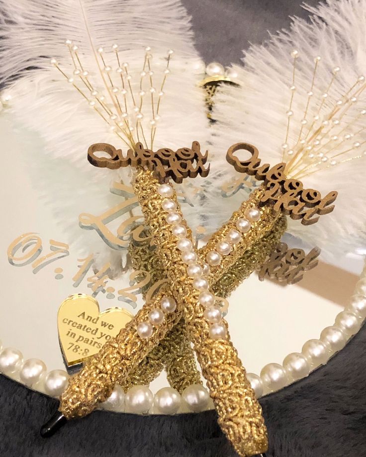 two brooches are sitting on top of a glass plate with pearls and feathers