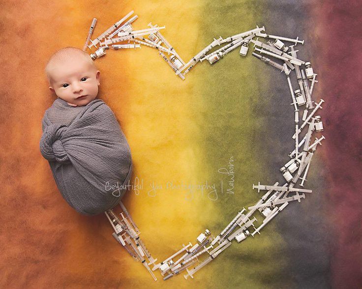 a baby wrapped in a blanket is laying next to a heart made out of legos