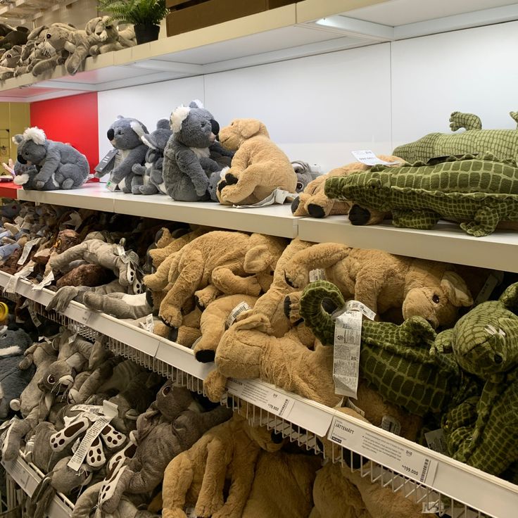 many stuffed animals are on shelves in a store