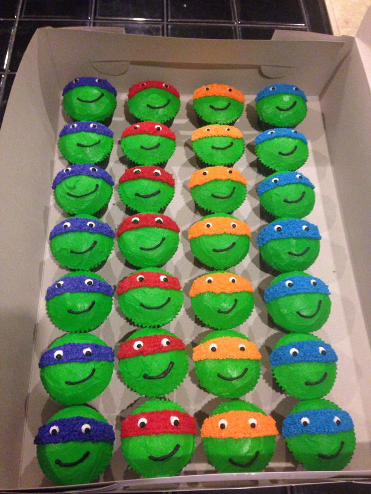 a box filled with cupcakes covered in green and red frosted teenage turtles