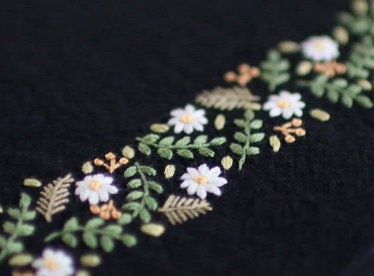 a close up view of some flowers and leaves on a black cloth with gold trim