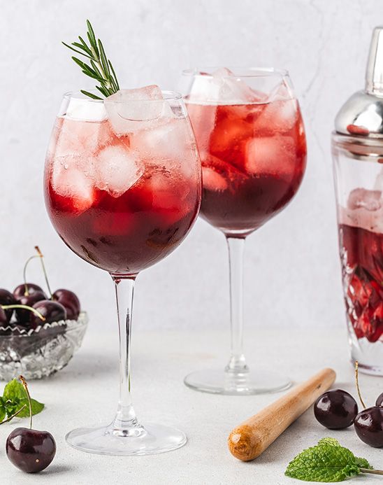 two glasses filled with red wine and cherries