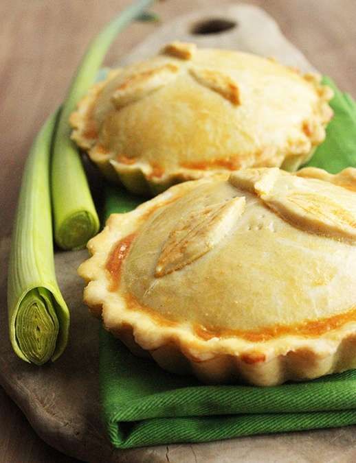 two pies sitting on top of a green cloth next to celery stalks