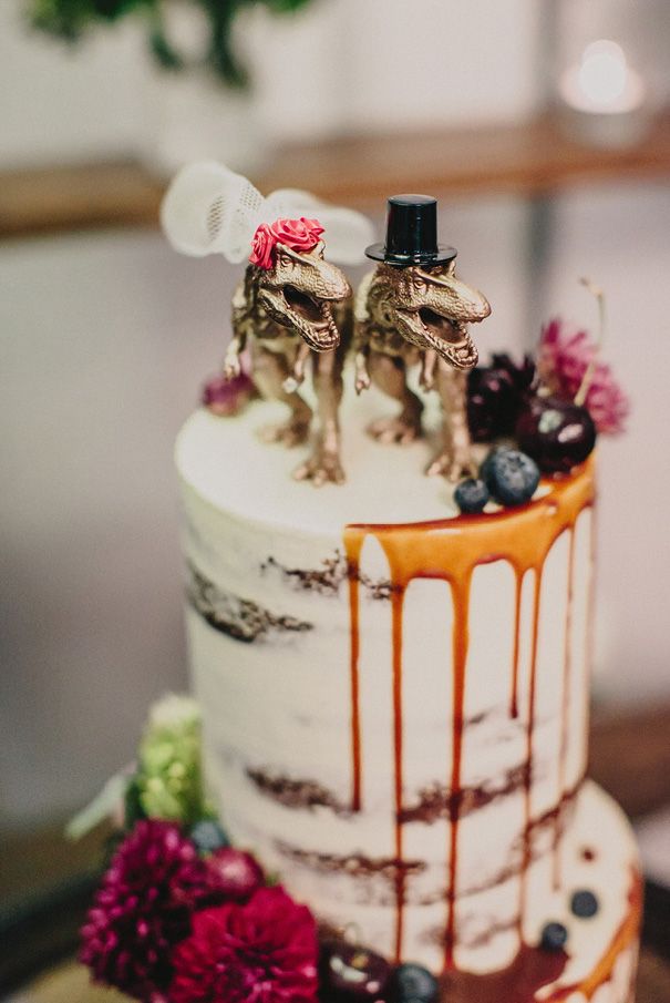 the wedding cake is decorated with figurines on top of it and drizzled with caramel